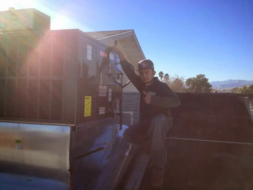 HVAC technician performing AC Tune-Up on a rooftop unit in Dayton